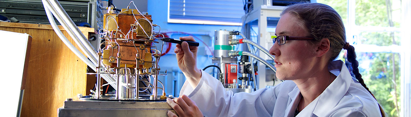 Woman in white lab coat adjusting wires on a machine