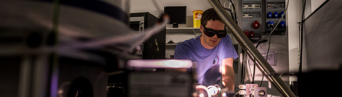 Man in blue t-shirt and protective glasses looking at equipment