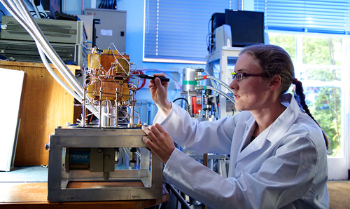 Woman in white lab coat adjusting wires on a machine